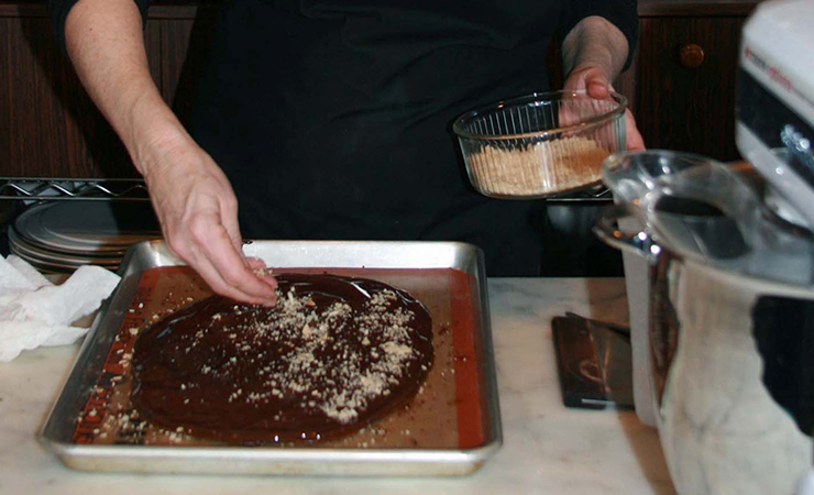 As more chocolate melts into the hardening toffee, Rose adds almonds.
